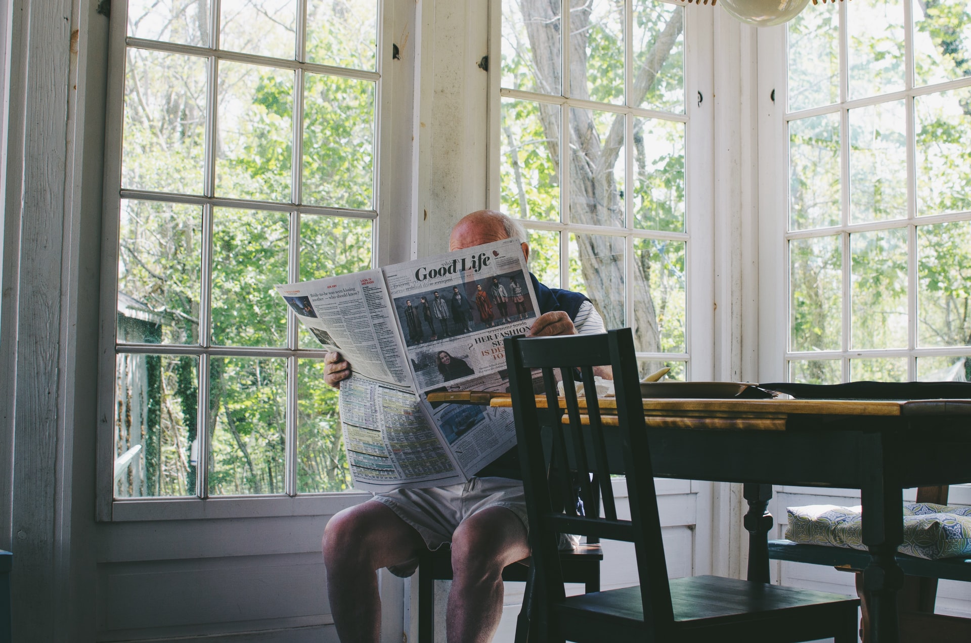 Photo of senior reading a newspaper at dinning room table